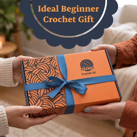 Two people exchange a Berstuk Crochet Kit gift box, orange with a navy yarn pattern and a blue ribbon bow, in a warm living room.