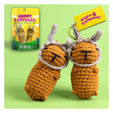 Crocheted capybara toys with packaging and tag on a green background