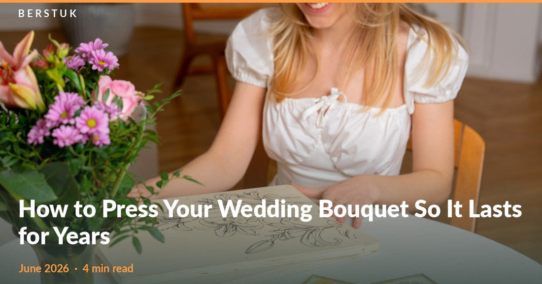 Woman at a table with a fresh summer bouquet, an open Berstuk XL Flower Press and two framed pressed-flower keepsakes
