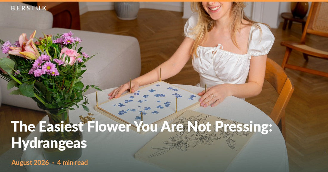 Woman arranging blue hydrangea florets on the open page of a Berstuk XL Flower Press