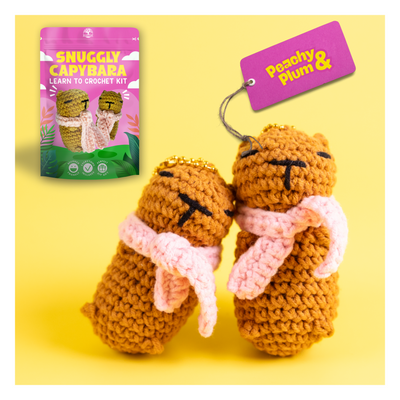 Crocheted capybara toys with packaging and tag on a yellow background
