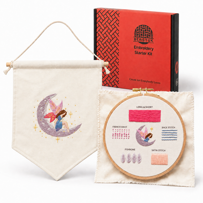 Embroidery Starter Kit by Berstuk, featuring a finished embroidered banner with a fairy on a crescent moon, an embroidery hoop showing sample stitches and thread, and the orange and dark green branded starter kit box in the background.