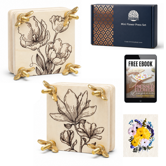 A mini flower press set shown on a white background, including two cream-colored wooden flower press blocks with gold metal corner supports and floral line drawings, a dark navy product box, a tablet displaying a free ebook, and a small floral artwork sample.