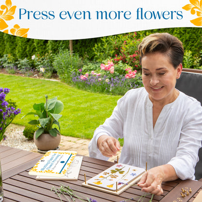 Woman arranging pressed flowers on a flower press at an outdoor garden table